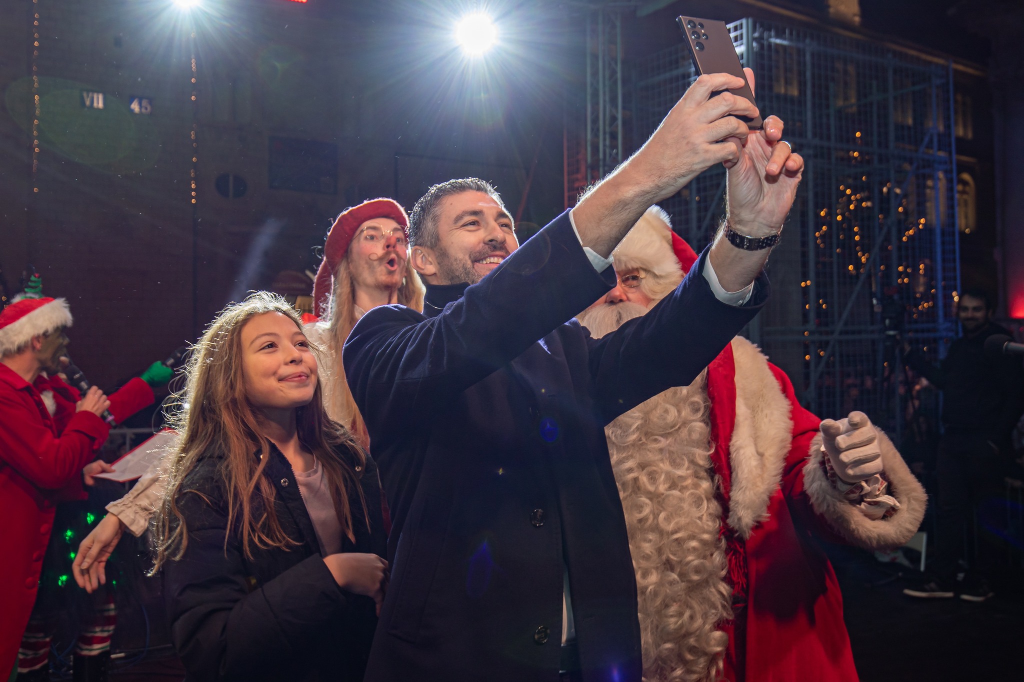 Man taking a selfie with Santa Claus, a girl and an elf on stage at the Dubrovnik Winter Festival