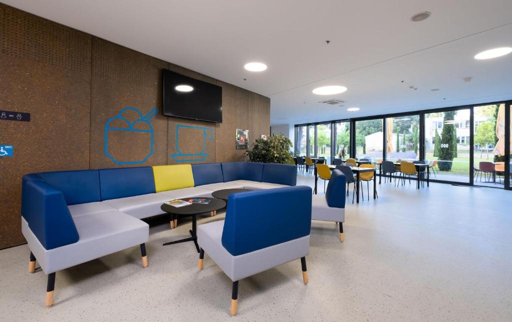 Lounge with blue sofas and a dining area with garden views at the Akademis Academia co-working space