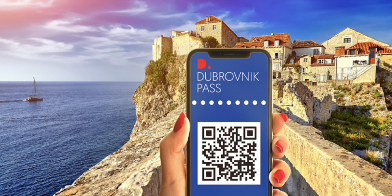 Hand holding a phone showing the Dubrovnik Pass QR code above the city walls and sea
