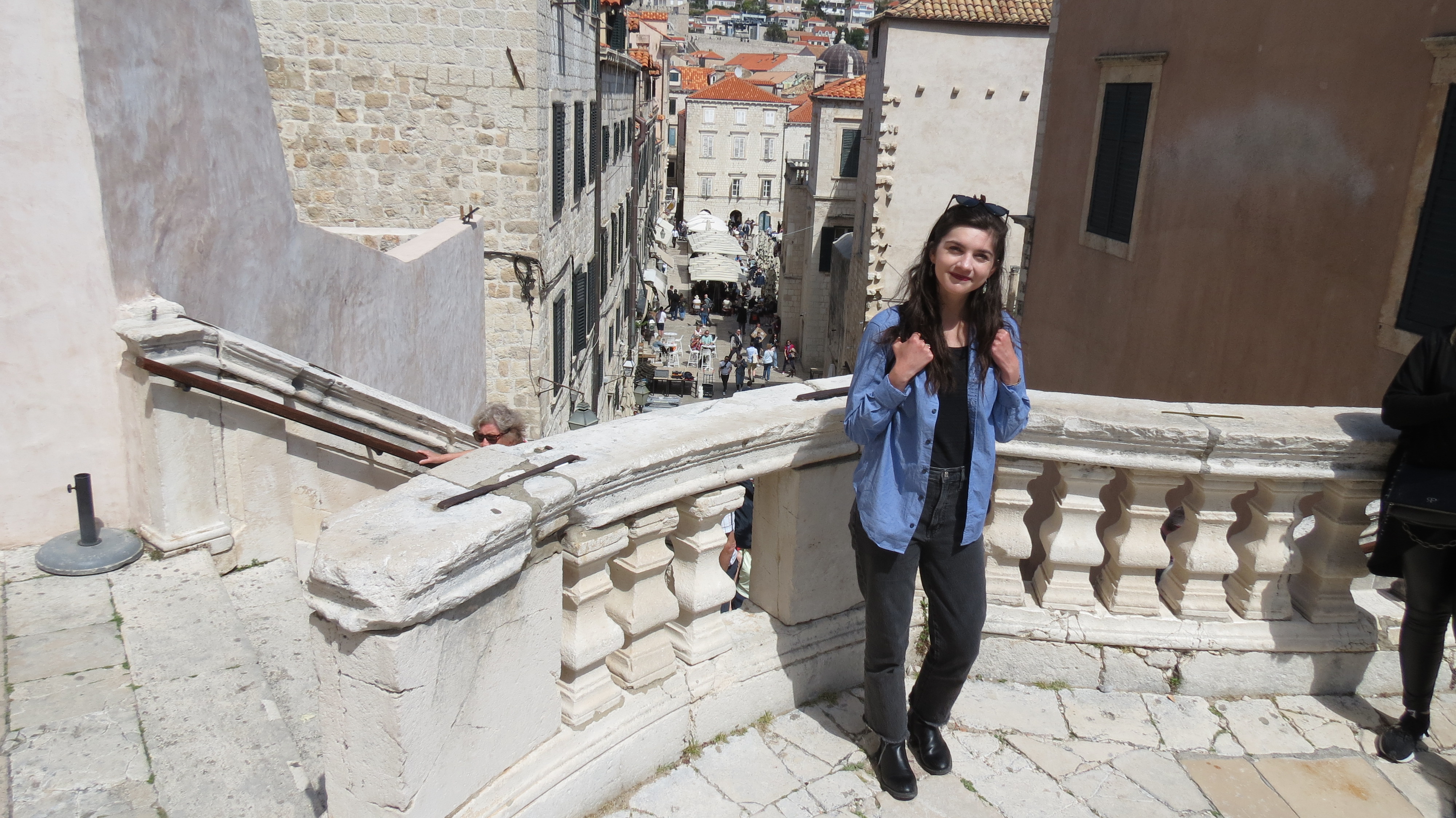 Yvonne Worden on a baroque stone staircase overlooking a busy square in Dubrovnik Old Town