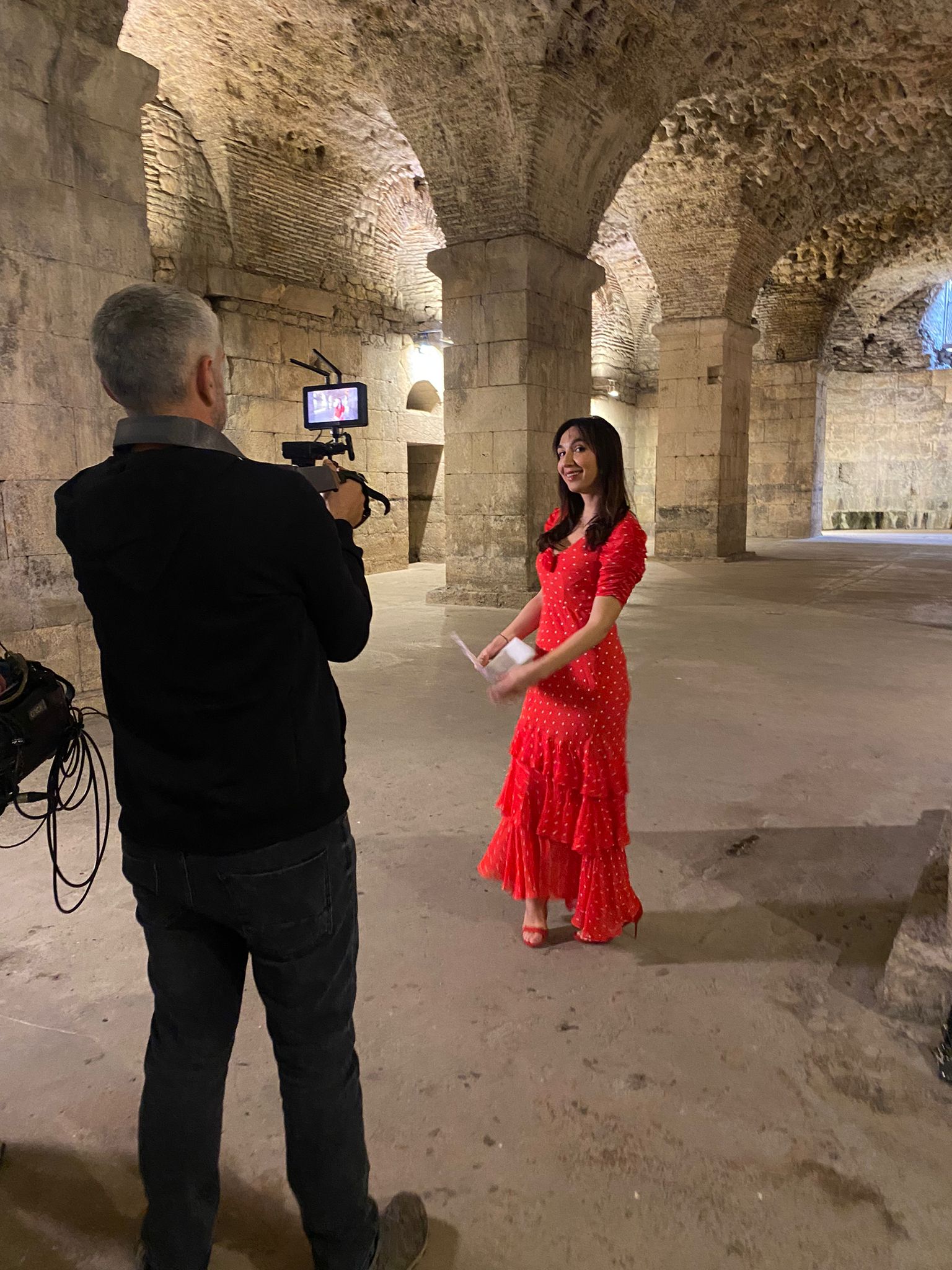 ITV cameraman filming a presenter in a red dress in the vaulted cellars of Diocletian's Palace in Split