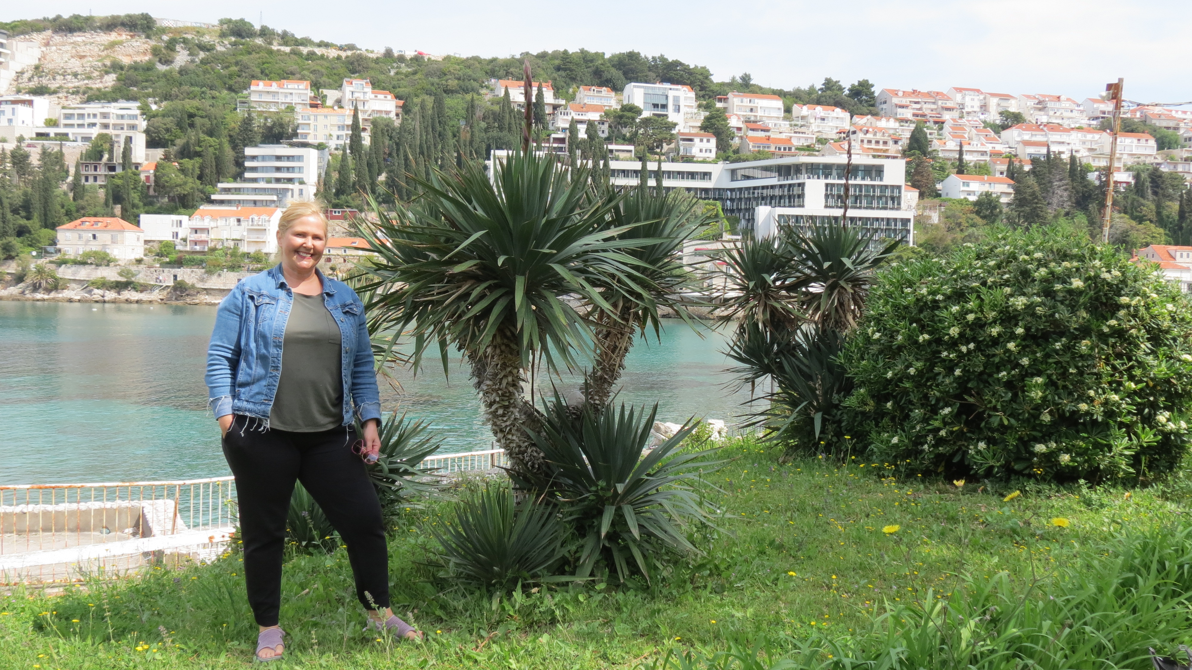 Kristie Sullivan standing on a grassy seafront among palms in Dubrovnik