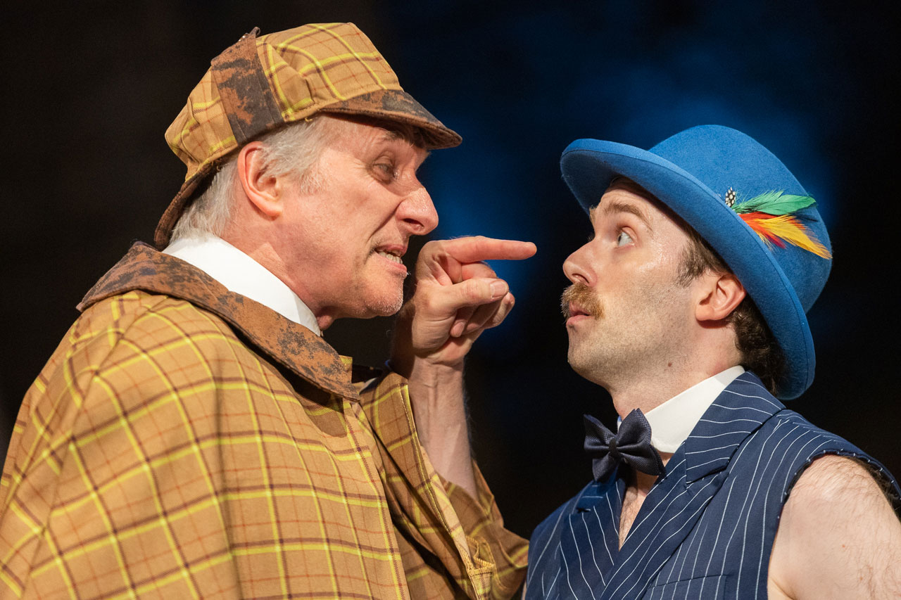 Two actors face to face in Around the World in 80 Days, one in a checked deerstalker, one in a blue bowler hat