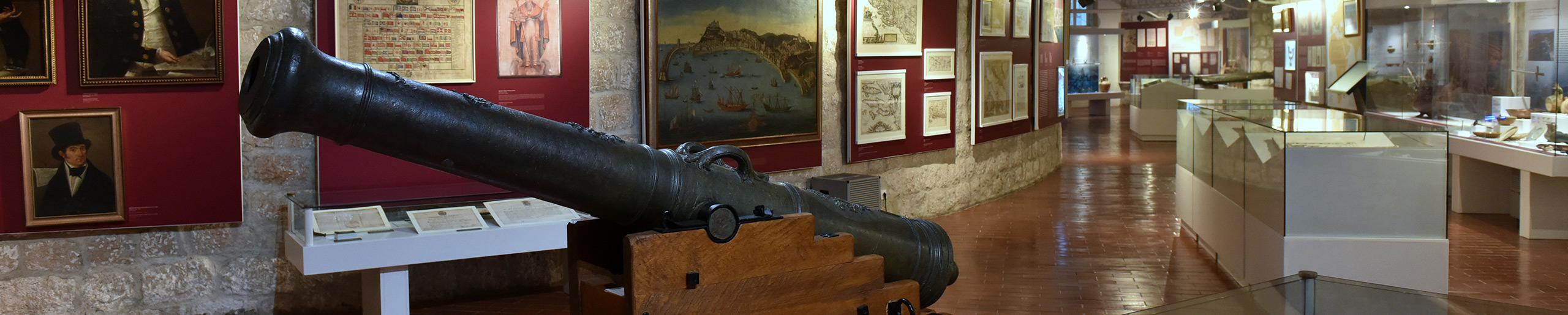 Maritime Museum hall with an old cannon, historic maps and ship paintings