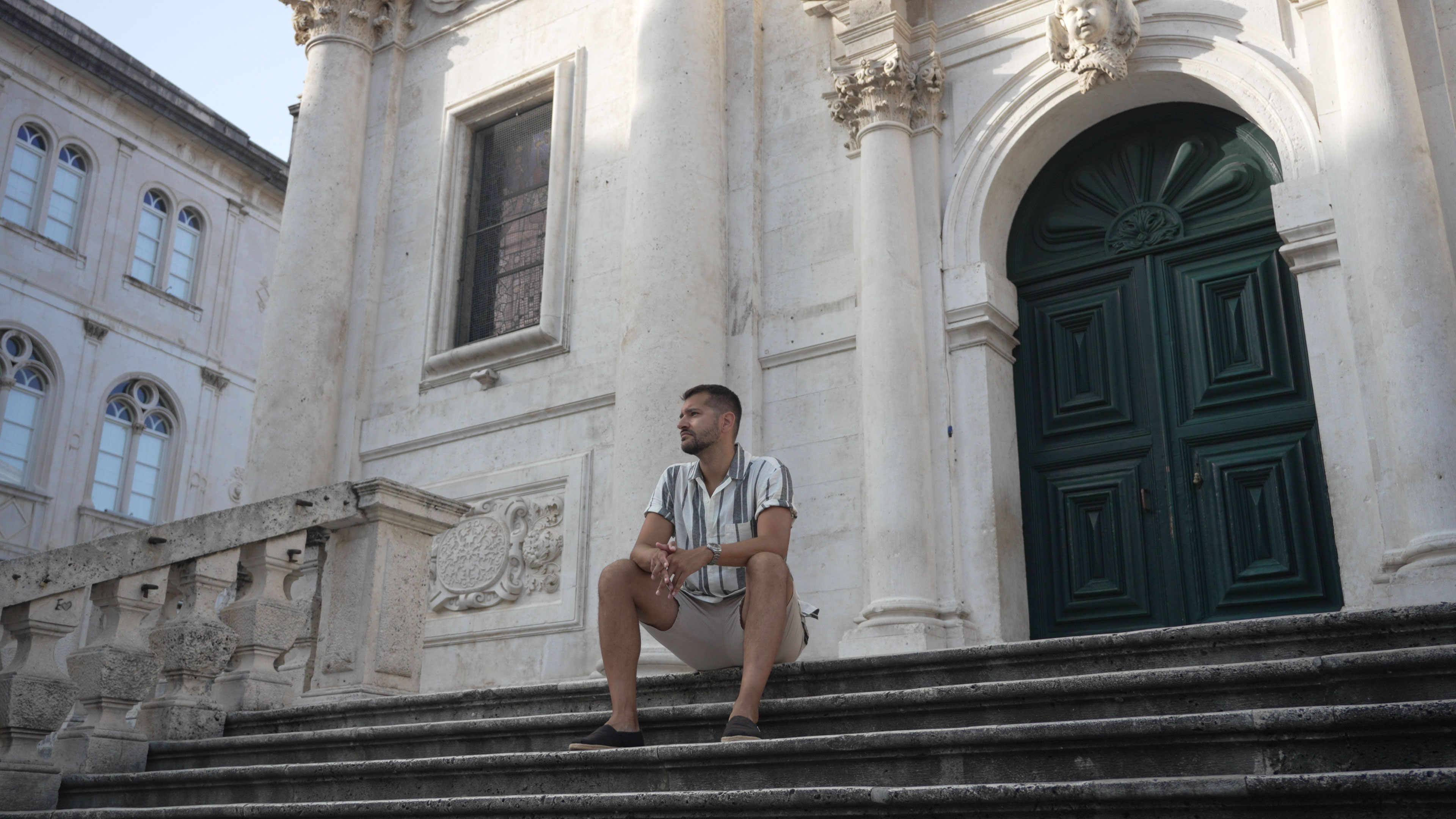 Daniel Hogston sitting on the steps of a baroque church in Dubrovnik Old Town