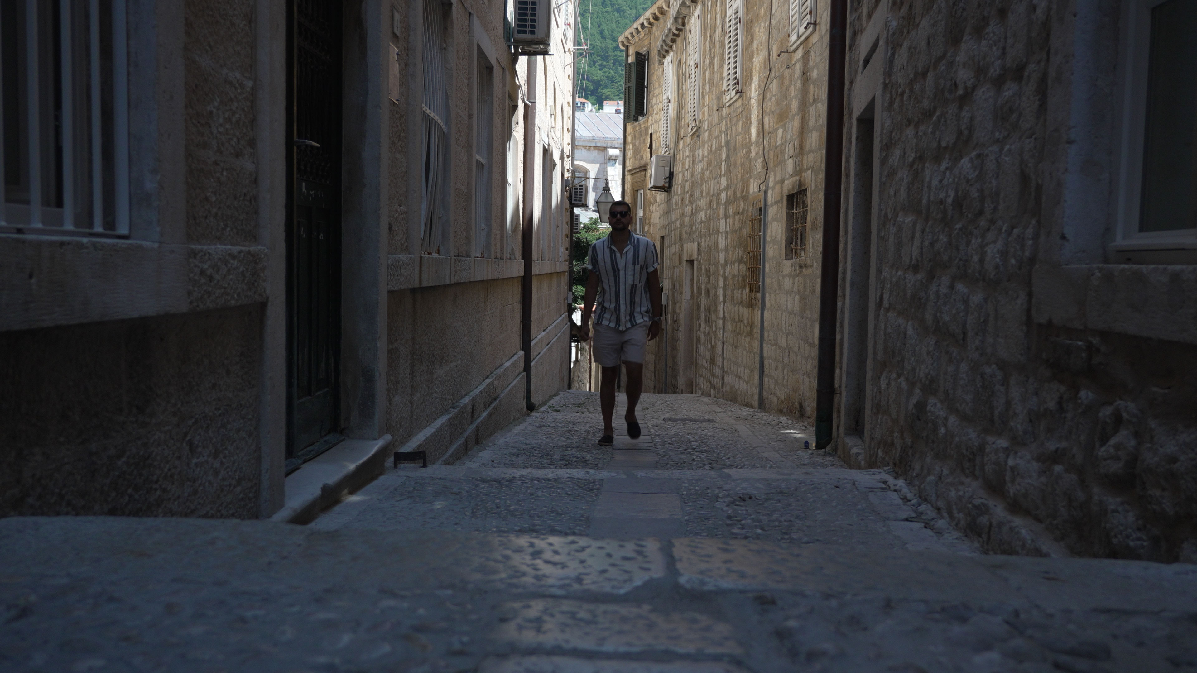 Daniel Hogston walking along a narrow shaded stone street in Dubrovnik Old Town