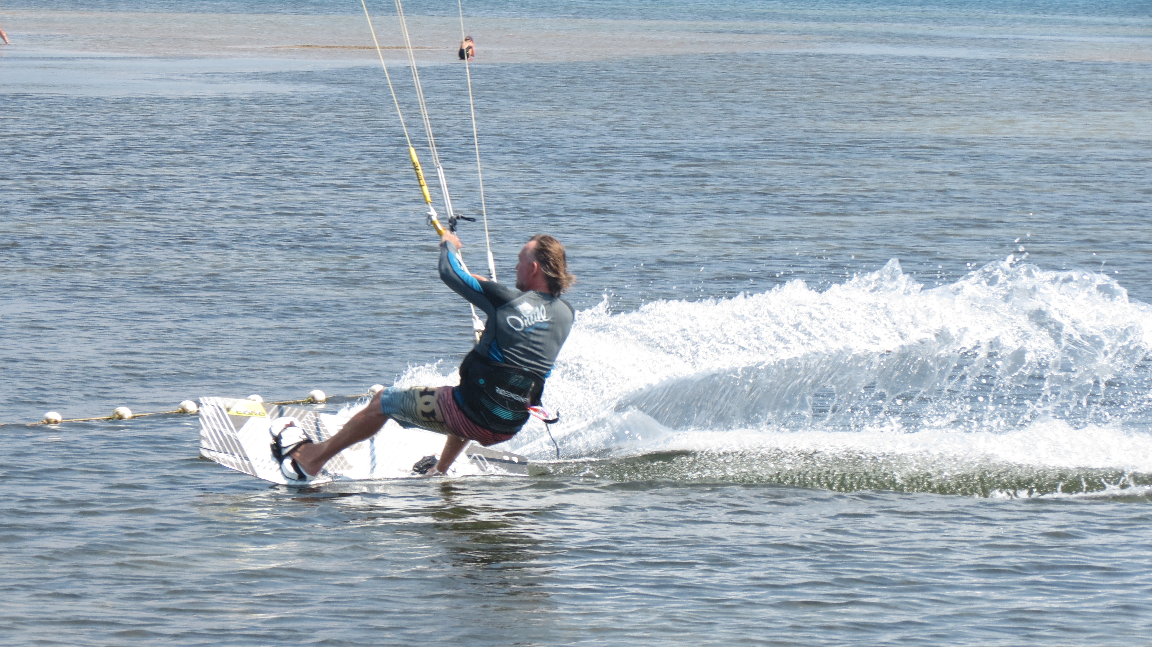 Kite surfer carving through the water and throwing up spray at the Neretva River mouth