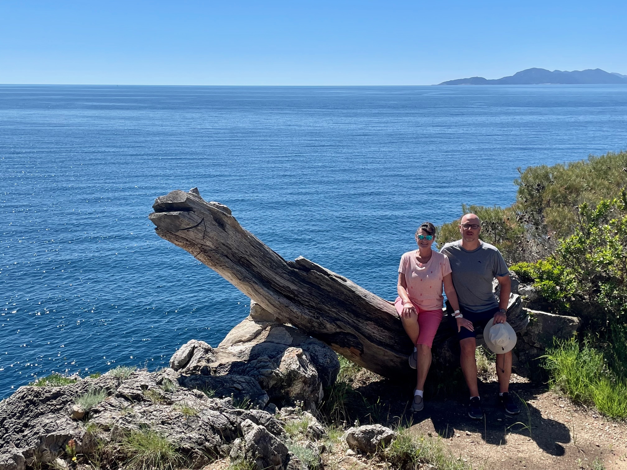 Marlee McCormick and Jeff Burkett sitting on a weathered log above the sea while hiking on Lopud