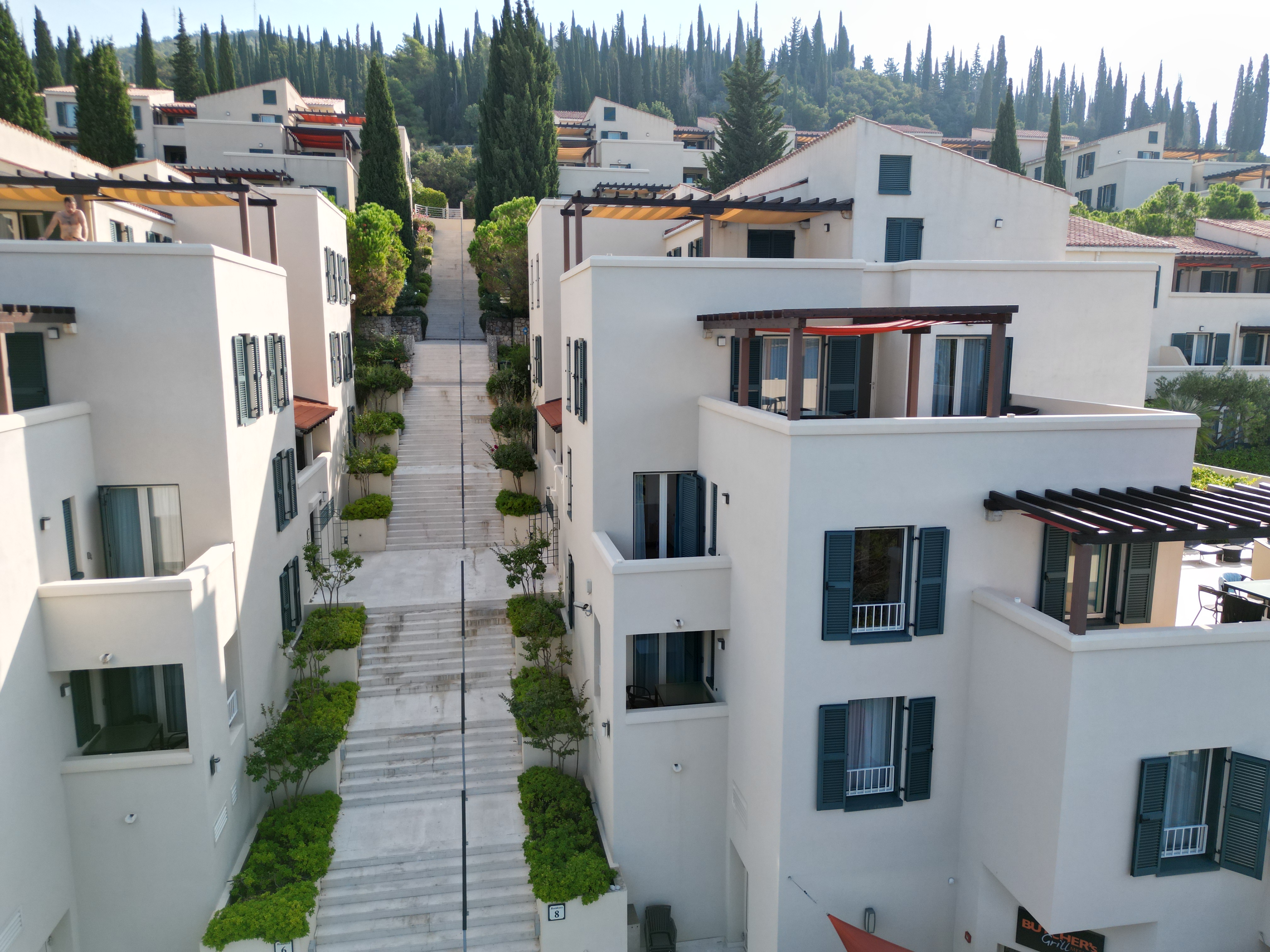 White apartment buildings with green shutters and a stepped walkway at Dubrovnik Sea View Residences
