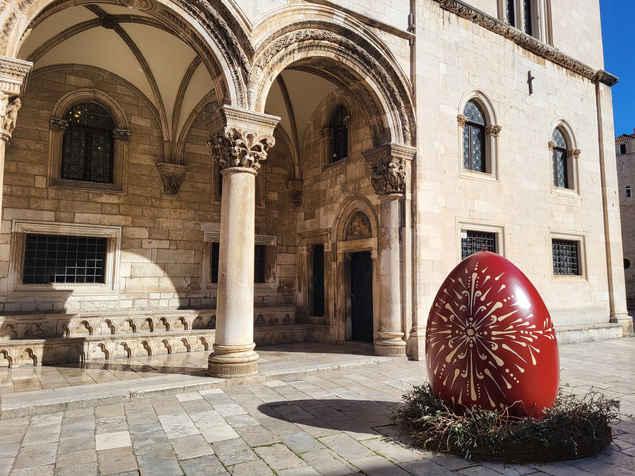 Large red decorated Easter egg in front of the arched portico of the Rector's Palace in Dubrovnik