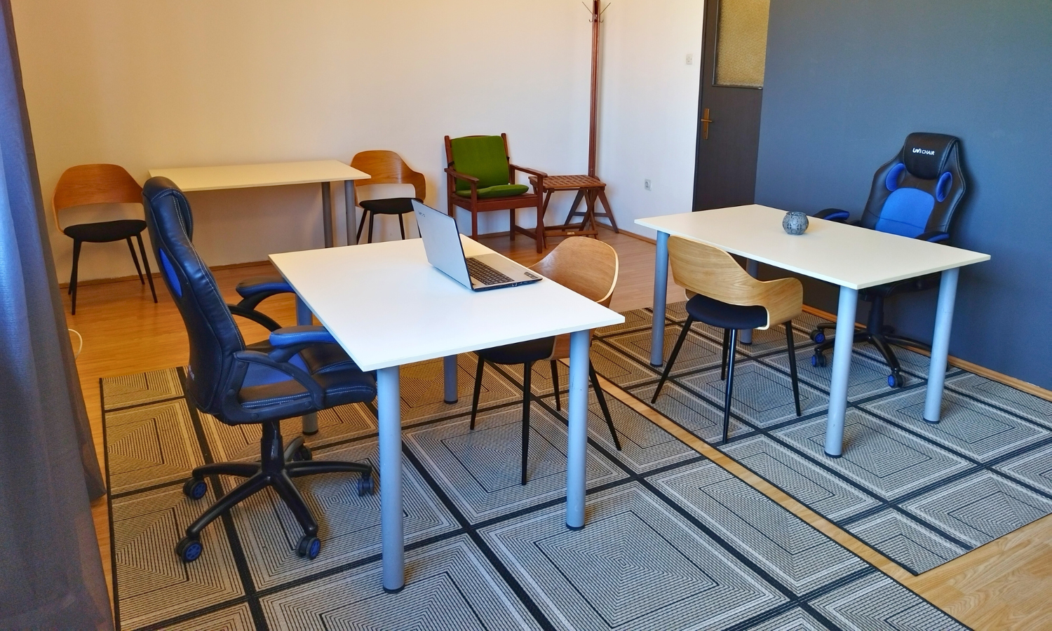 Co-working room at TUP with white desks, office chairs, a laptop and a patterned rug