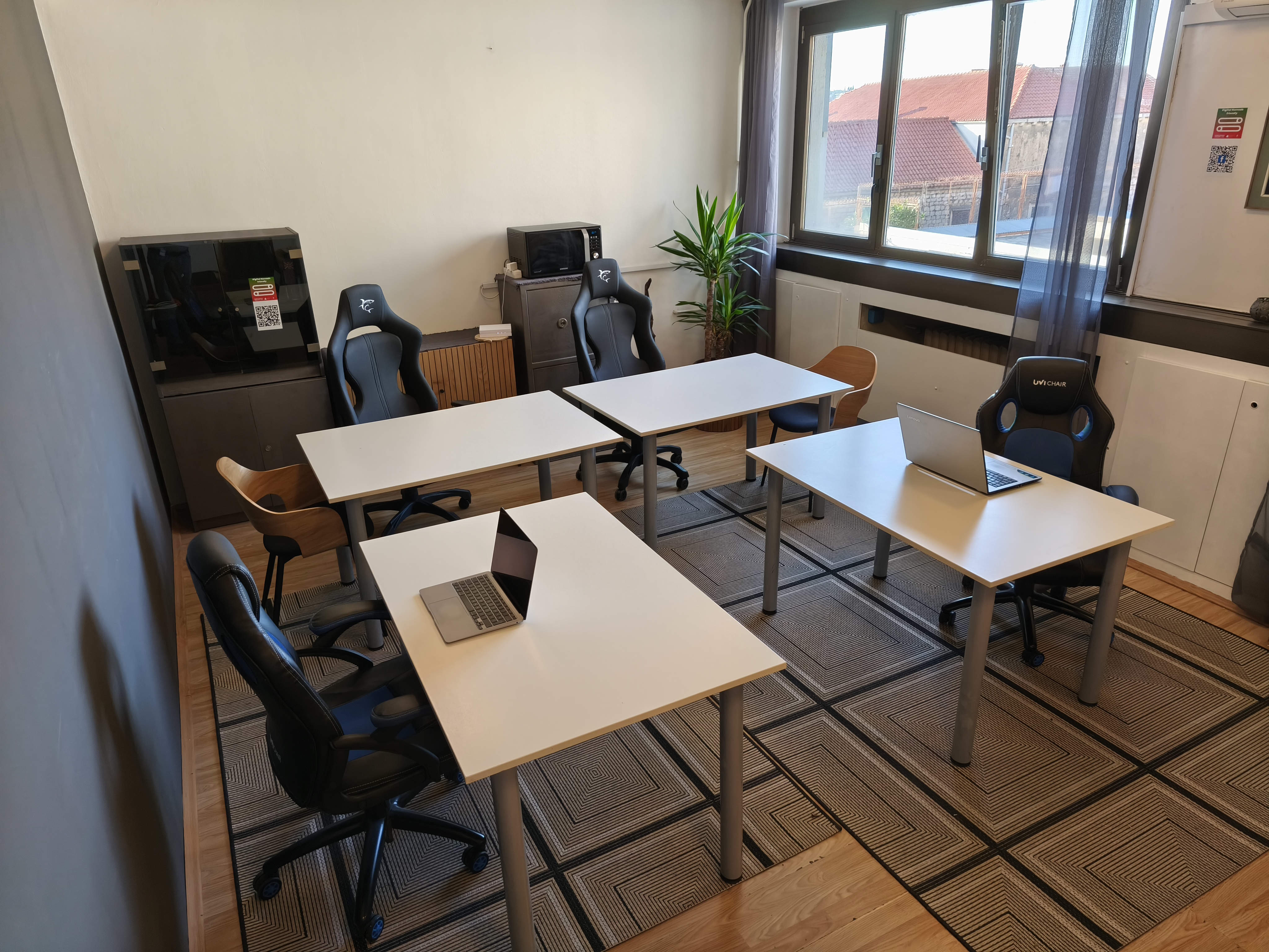 Dubrovnik co-working space with white desks, laptops and gaming chairs by the window