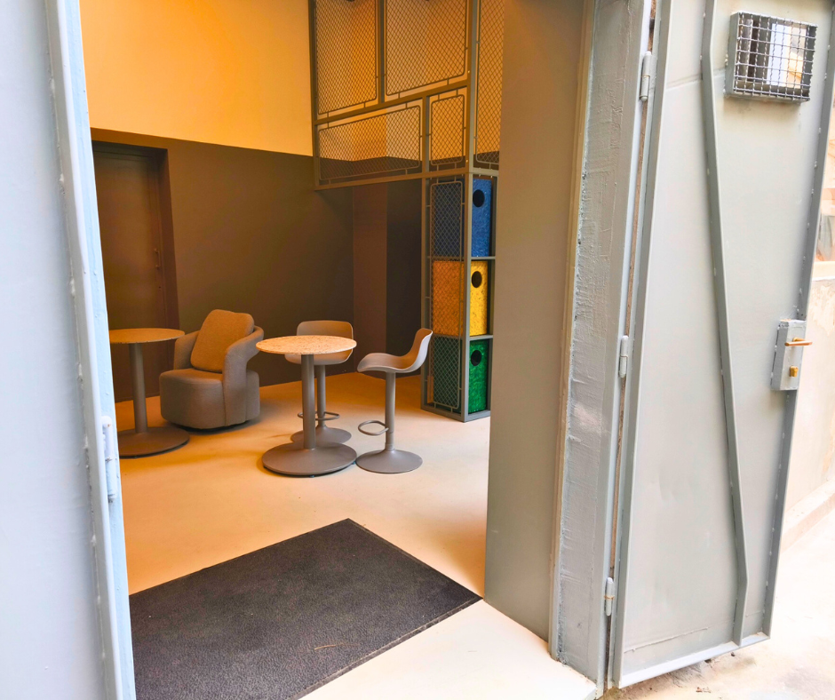Open steel door leading into Offline Space with lounge chairs and bar tables in the TUP building