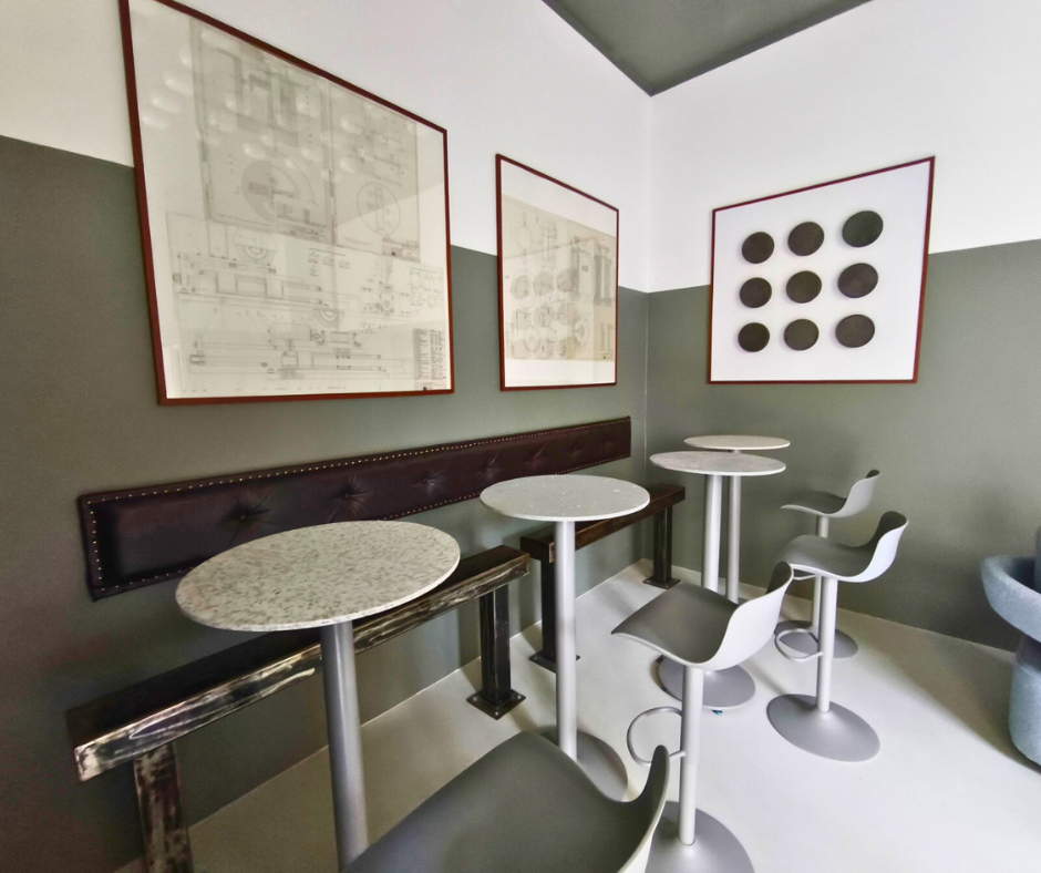 Corner of Offline Space with bar tables, stools and framed technical drawings from the old factory