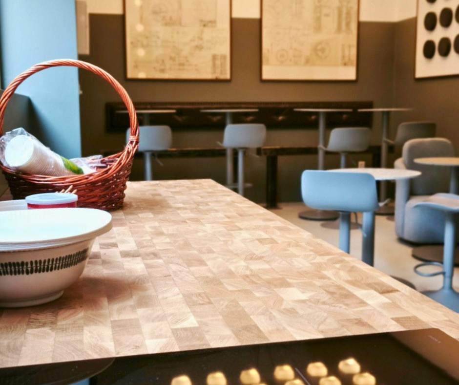 Kitchen counter with a basket and bowl overlooking bar stools and tables in Offline Space